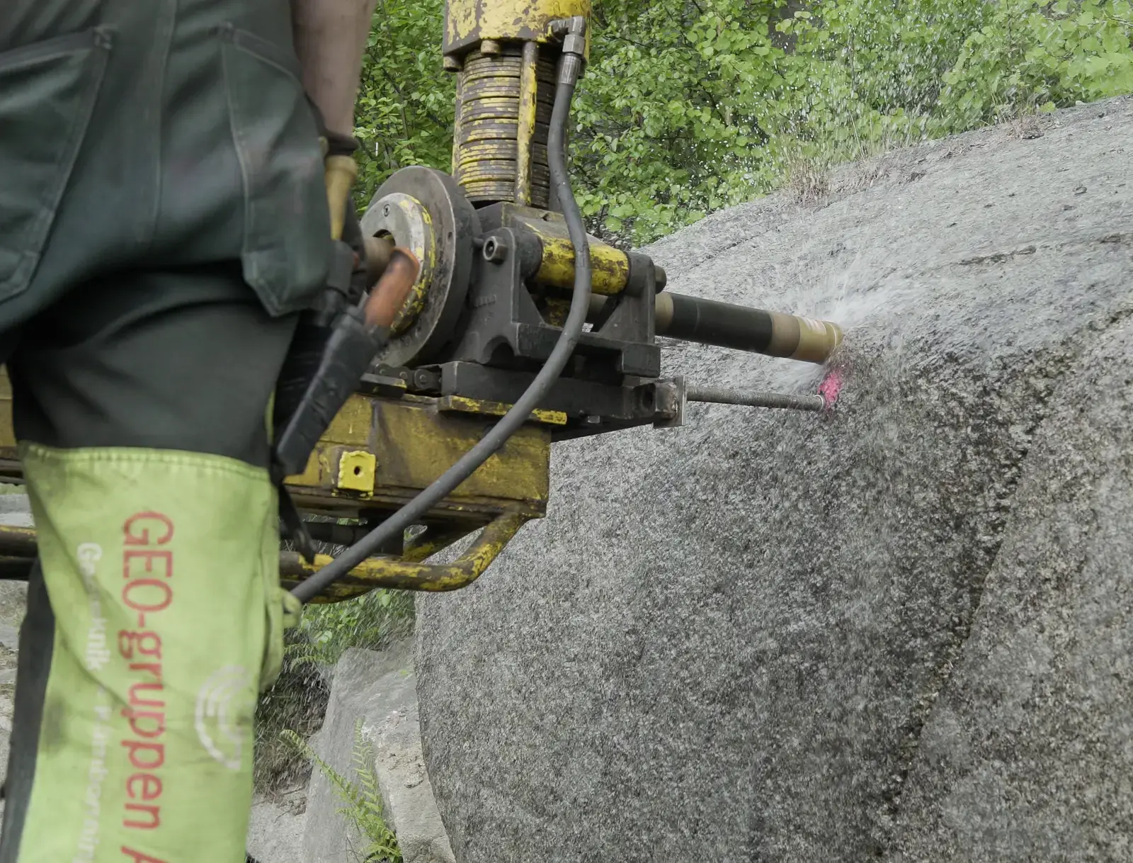 En arbetare från GEO-gruppen borrar i ett stort stenblock.